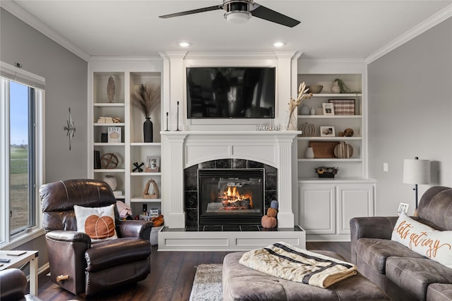 living room featuring ornamental molding, dark hardwood / wood-style floors, a tile fireplace, and ceiling fan