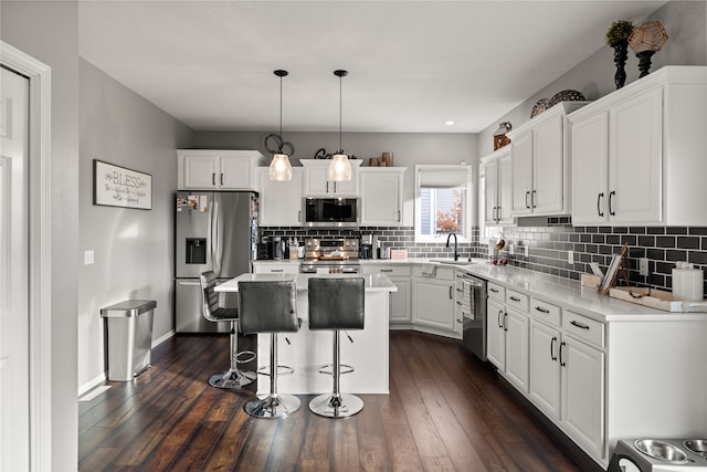 kitchen with a center island, stainless steel appliances, pendant lighting, white cabinets, and dark wood-type flooring