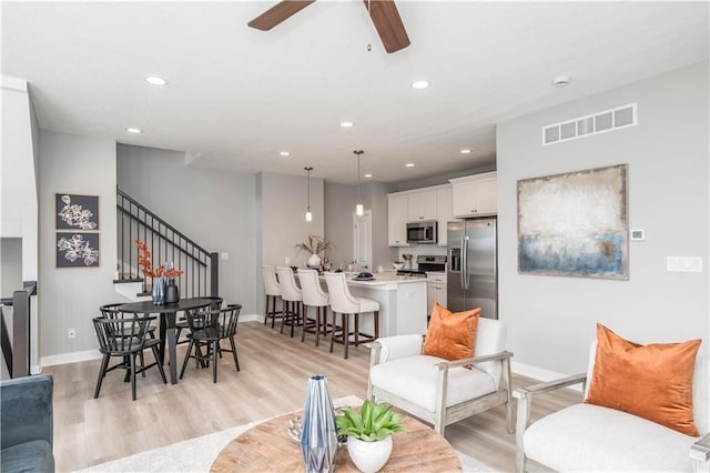 living room featuring ceiling fan and light hardwood / wood-style flooring