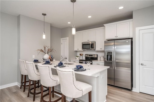 kitchen with sink, appliances with stainless steel finishes, hanging light fixtures, and white cabinetry