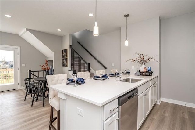 kitchen with dishwasher, hanging light fixtures, sink, white cabinetry, and light hardwood / wood-style floors