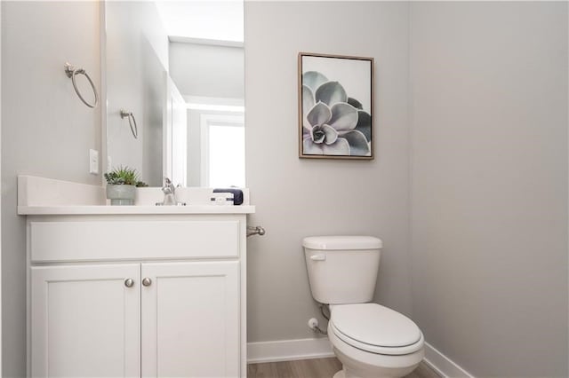 bathroom featuring toilet, hardwood / wood-style flooring, and vanity