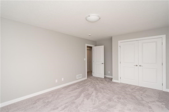 unfurnished bedroom featuring light carpet and a closet