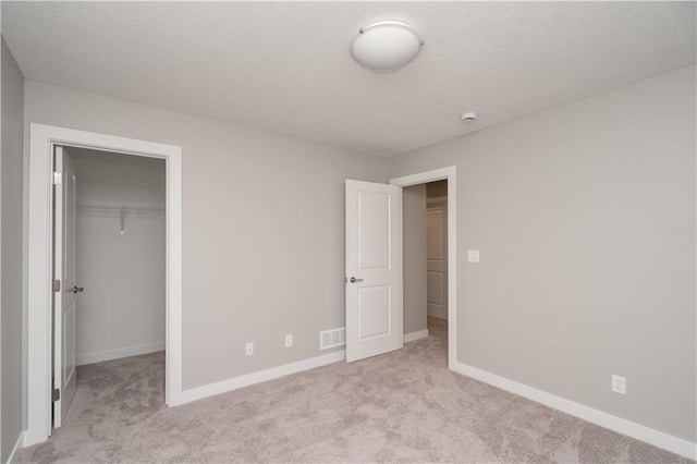 unfurnished bedroom with a closet, a spacious closet, and light colored carpet