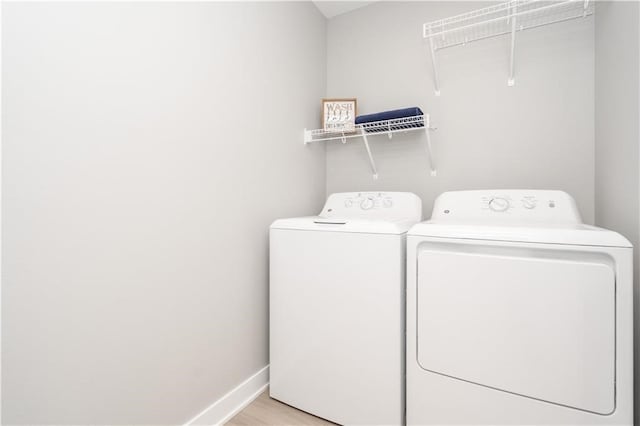 laundry area with light hardwood / wood-style flooring and washer and clothes dryer