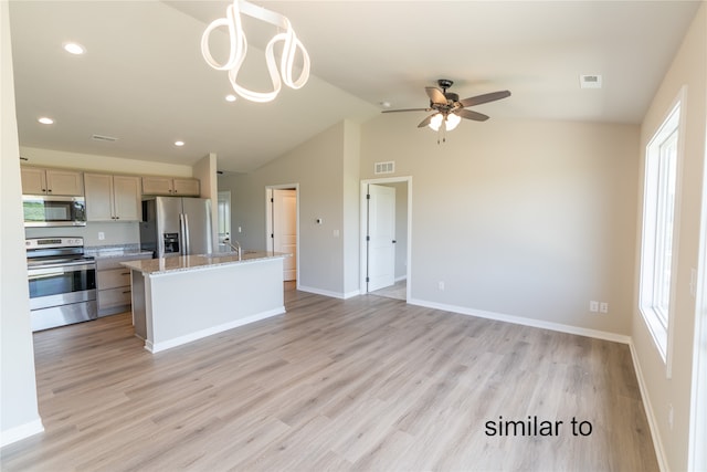 kitchen with a kitchen island, stainless steel appliances, light stone countertops, vaulted ceiling, and light hardwood / wood-style floors