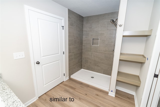 bathroom featuring hardwood / wood-style floors and tiled shower