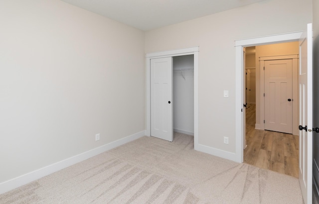 unfurnished bedroom featuring a closet, baseboards, and light carpet