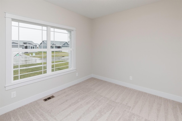 spare room featuring plenty of natural light, baseboards, visible vents, and carpet floors