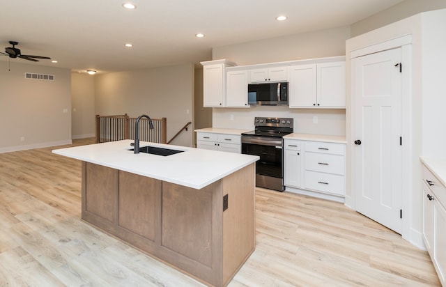 kitchen featuring a center island with sink, white cabinets, sink, ceiling fan, and appliances with stainless steel finishes