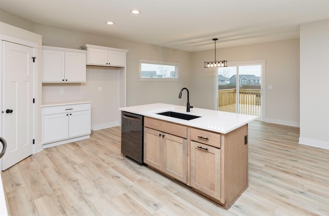 kitchen with light wood finished floors, a sink, light countertops, dishwashing machine, and baseboards