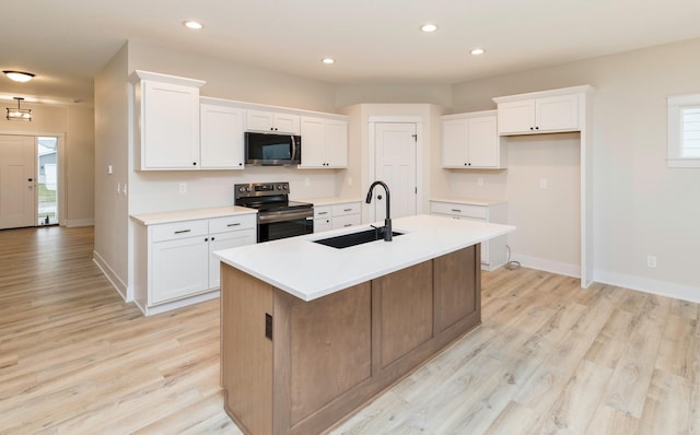 kitchen with white cabinets, appliances with stainless steel finishes, light wood-type flooring, and a sink