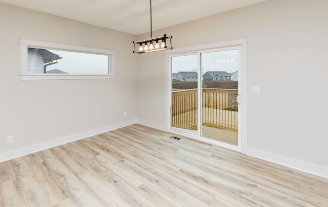 unfurnished room featuring visible vents, wood finished floors, and baseboards