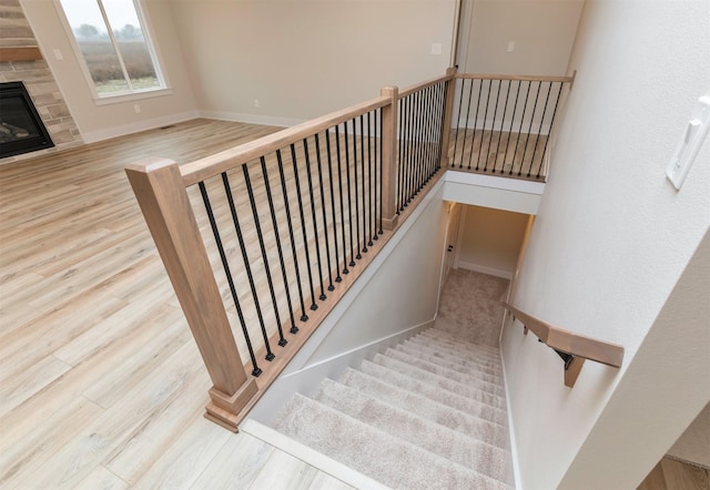 stairs with a glass covered fireplace, baseboards, and wood finished floors