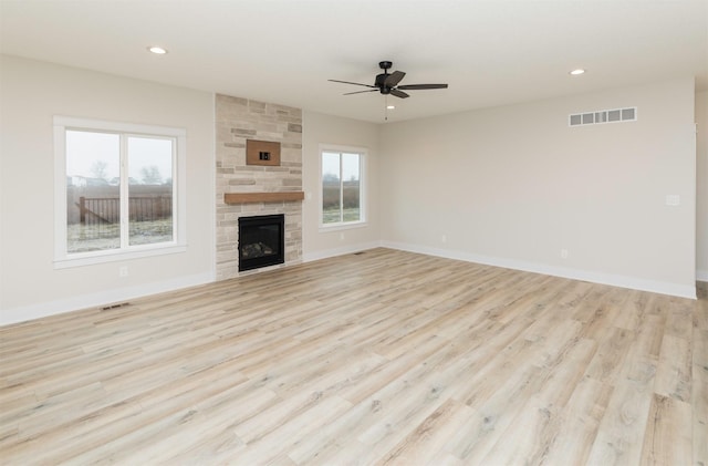 unfurnished living room featuring baseboards, light wood-style floors, visible vents, and a large fireplace