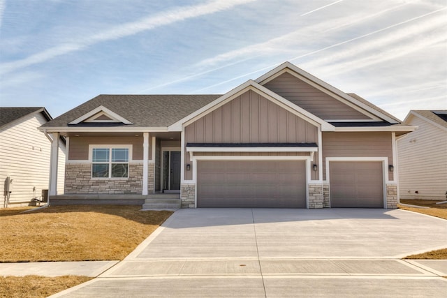 craftsman house with stone siding, an attached garage, driveway, and roof with shingles