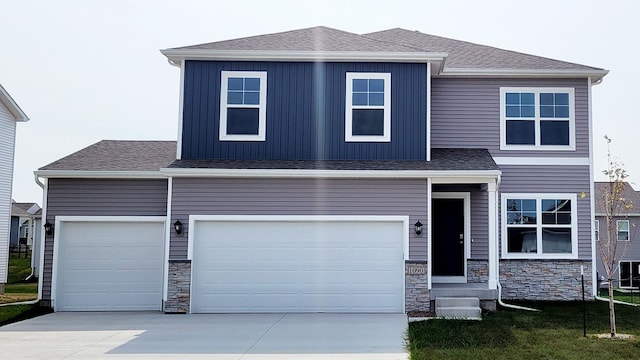 view of front of property featuring concrete driveway, stone siding, and a shingled roof