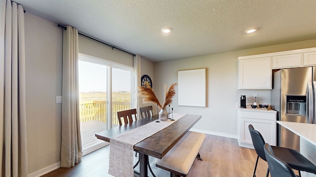 dining space with light wood-type flooring and a textured ceiling