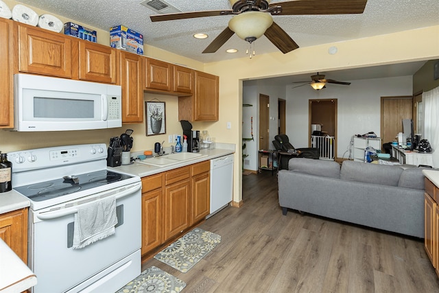 kitchen with light hardwood / wood-style floors, a textured ceiling, sink, and white appliances