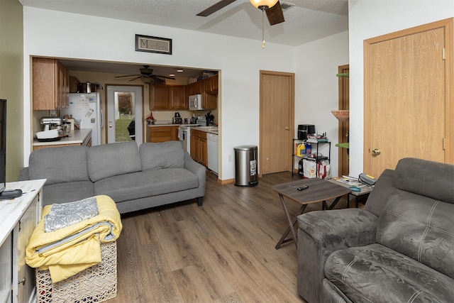 living room featuring ceiling fan, hardwood / wood-style flooring, and a textured ceiling