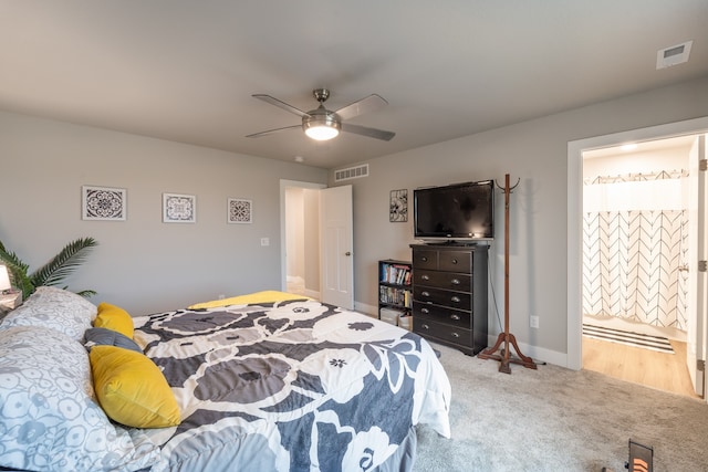 bedroom featuring light carpet, ensuite bath, and ceiling fan