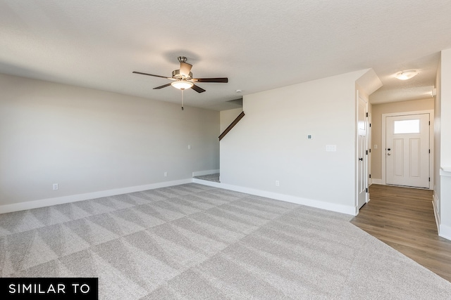 carpeted spare room with a textured ceiling and ceiling fan