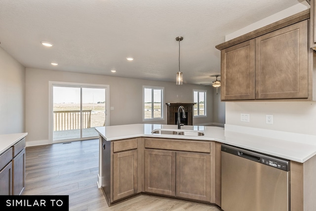 kitchen with sink, dishwasher, light wood-type flooring, kitchen peninsula, and hanging light fixtures