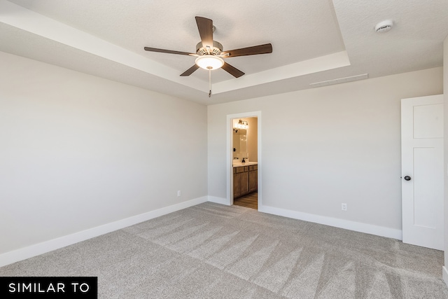 spare room featuring ceiling fan, a textured ceiling, a tray ceiling, and light colored carpet