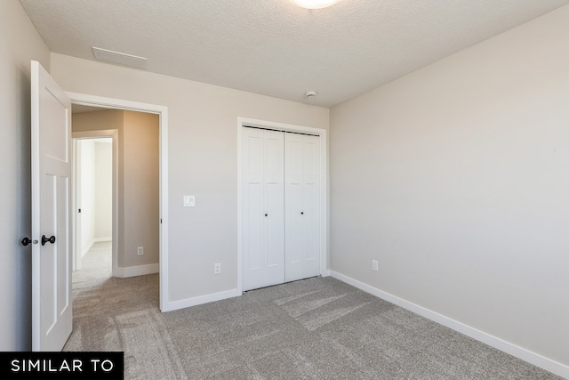 unfurnished bedroom with light carpet, a closet, and a textured ceiling