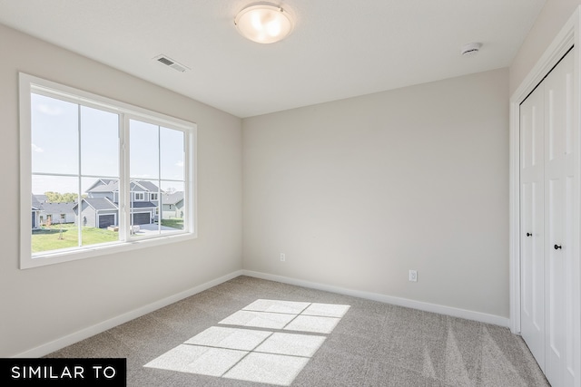 unfurnished bedroom featuring a closet and light colored carpet