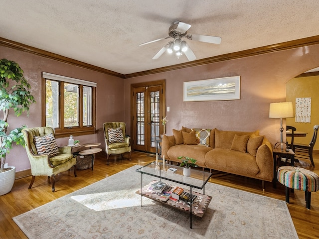 living room featuring a textured ceiling, crown molding, wood-type flooring, and ceiling fan