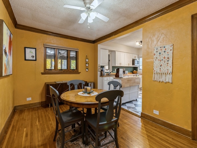 dining room with crown molding, a textured ceiling, and light wood-type flooring