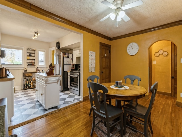 dining area featuring ceiling fan, a textured ceiling, light hardwood / wood-style flooring, and ornamental molding