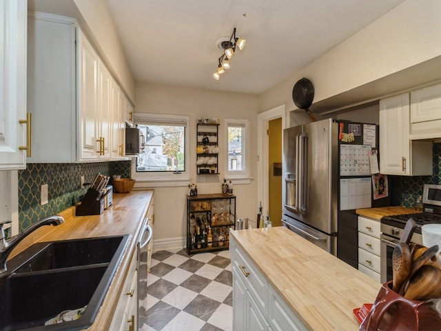 kitchen featuring appliances with stainless steel finishes, white cabinetry, wooden counters, and sink