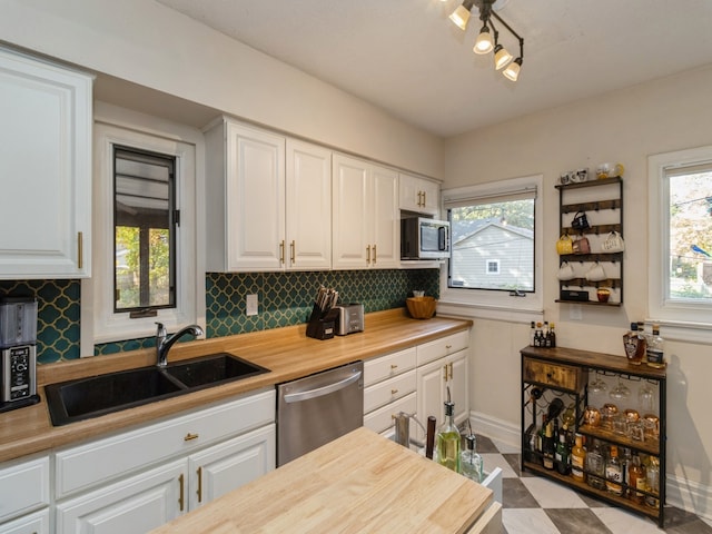 kitchen with backsplash, stainless steel appliances, sink, and white cabinets