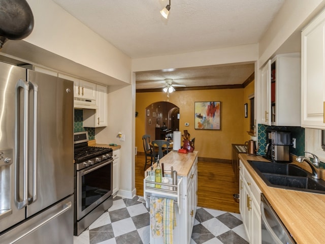 kitchen with light hardwood / wood-style flooring, stainless steel appliances, wood counters, sink, and white cabinetry