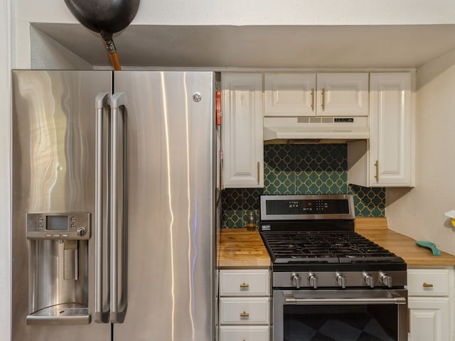 kitchen with wood counters, appliances with stainless steel finishes, white cabinets, and tasteful backsplash