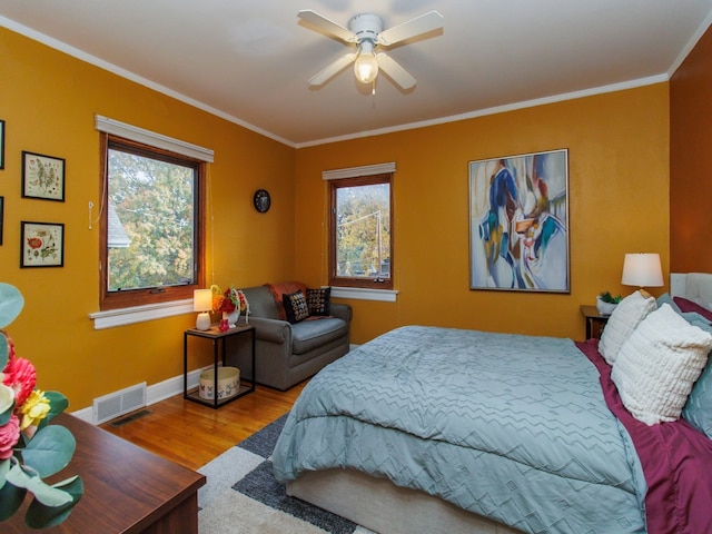 bedroom with ornamental molding, hardwood / wood-style floors, multiple windows, and ceiling fan