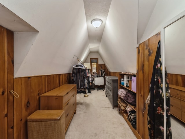 bonus room with a textured ceiling, wood walls, light colored carpet, and vaulted ceiling