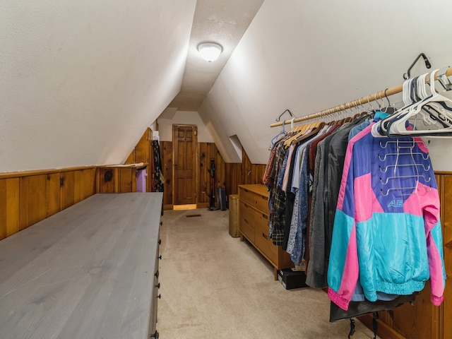 walk in closet with light carpet and vaulted ceiling