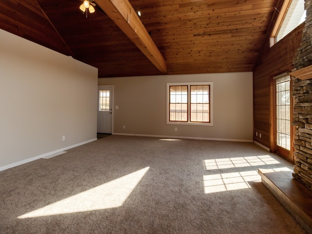 spare room with wood ceiling, a stone fireplace, light carpet, ceiling fan, and beamed ceiling