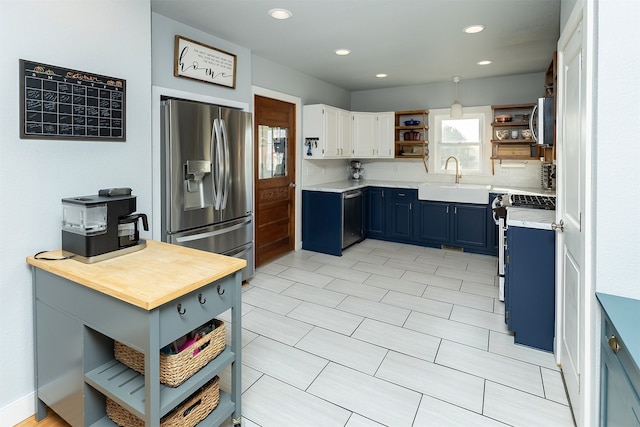 kitchen featuring stainless steel appliances, sink, blue cabinetry, white cabinetry, and tasteful backsplash