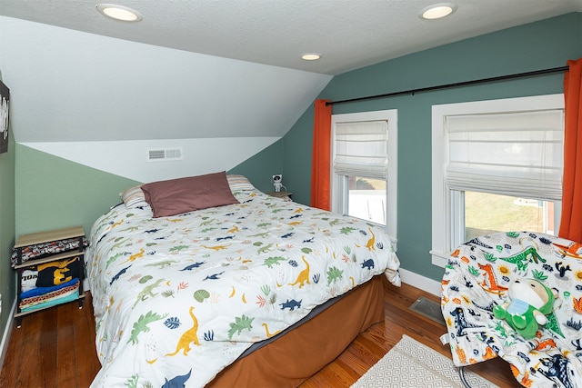 bedroom featuring hardwood / wood-style floors, vaulted ceiling, and a textured ceiling