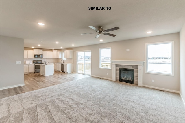 unfurnished living room featuring recessed lighting, light colored carpet, baseboards, and a tile fireplace