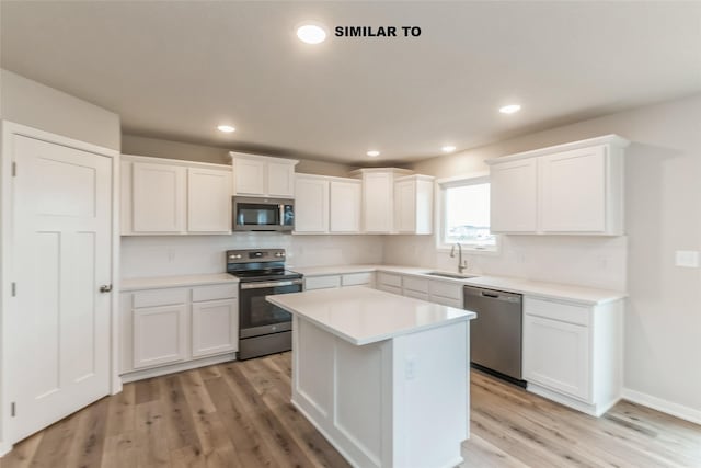 kitchen featuring a kitchen island, a sink, white cabinets, light countertops, and appliances with stainless steel finishes