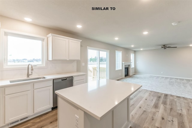 kitchen with a sink, a kitchen island, white cabinetry, and dishwasher