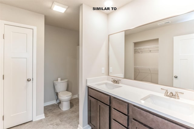 bathroom featuring visible vents, double vanity, a sink, and toilet