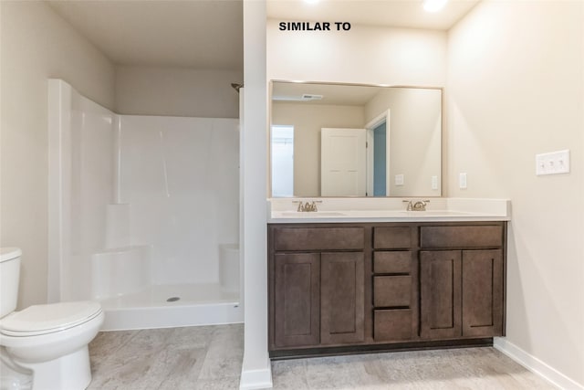 bathroom with double vanity, walk in shower, a sink, and toilet