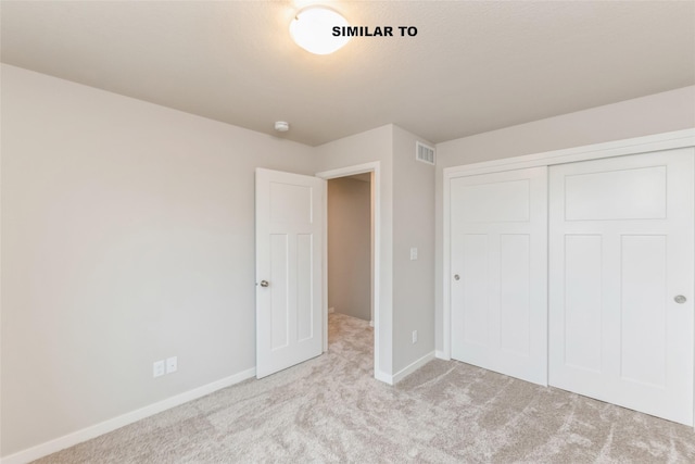 unfurnished bedroom with baseboards, visible vents, a closet, and light colored carpet