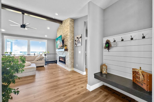 living room featuring lofted ceiling with beams, wood-type flooring, a fireplace, and ceiling fan